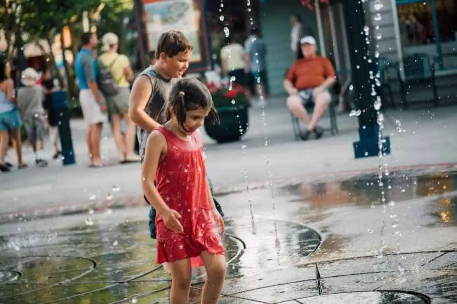 Young kids having fun playing with Water Fountains at Disney World at the beginning of summer